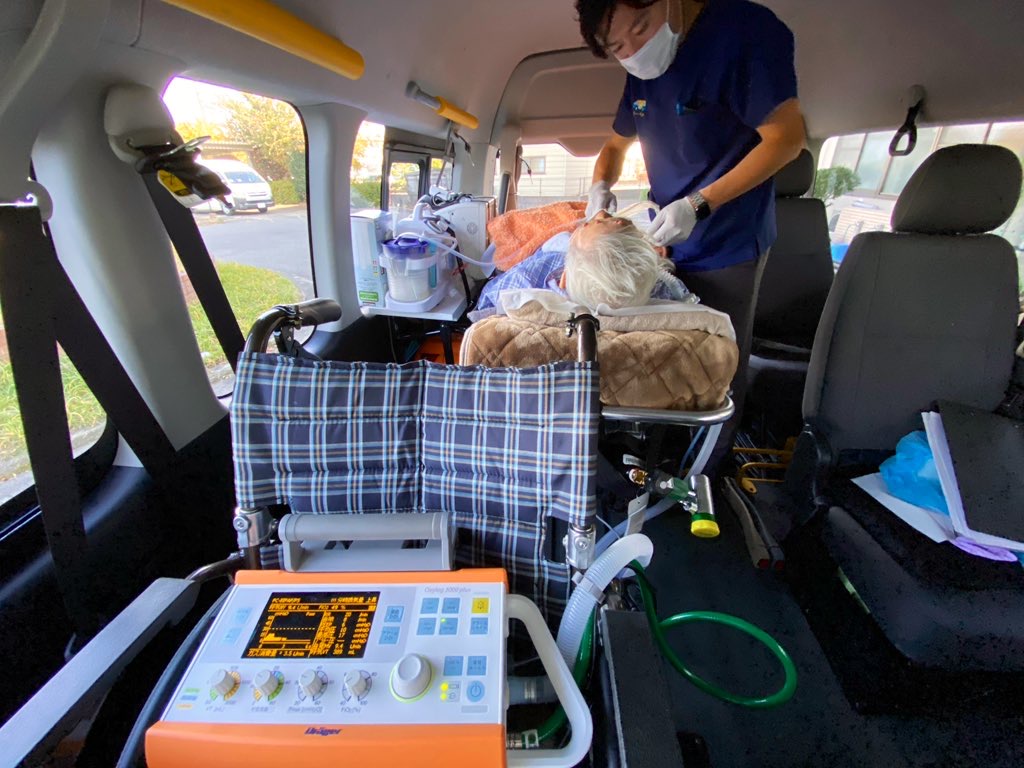 民間救急車の車内で、人工呼吸器をつけた方のそばで対応するリーベルのスタッフ